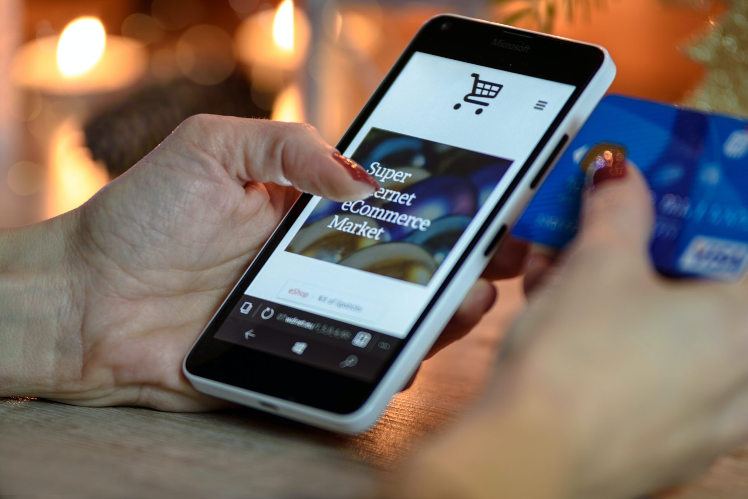 A hands using a cellphone while holding a card